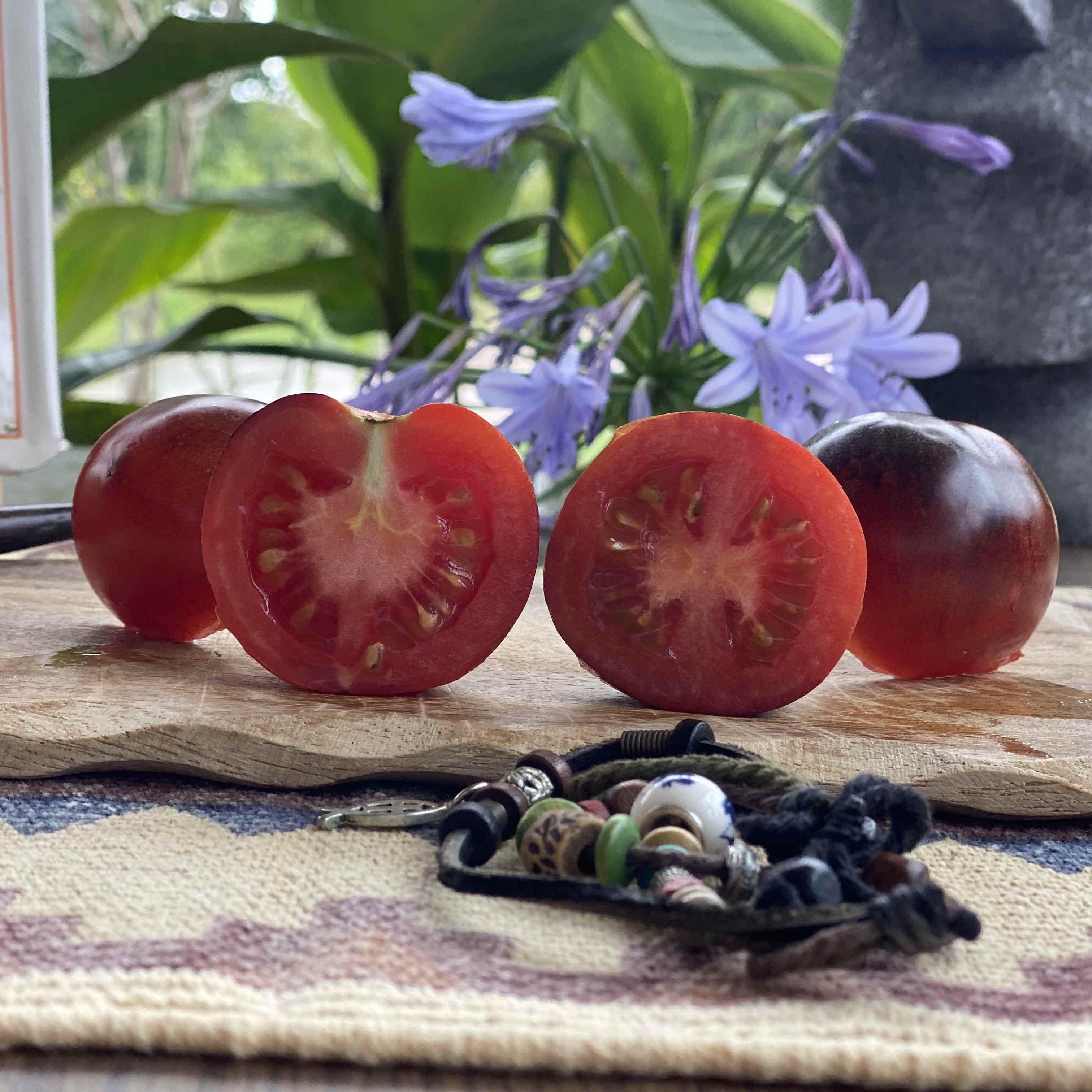 Eine quer aufgeschnittene rot/lila Tomate auf einem Brett