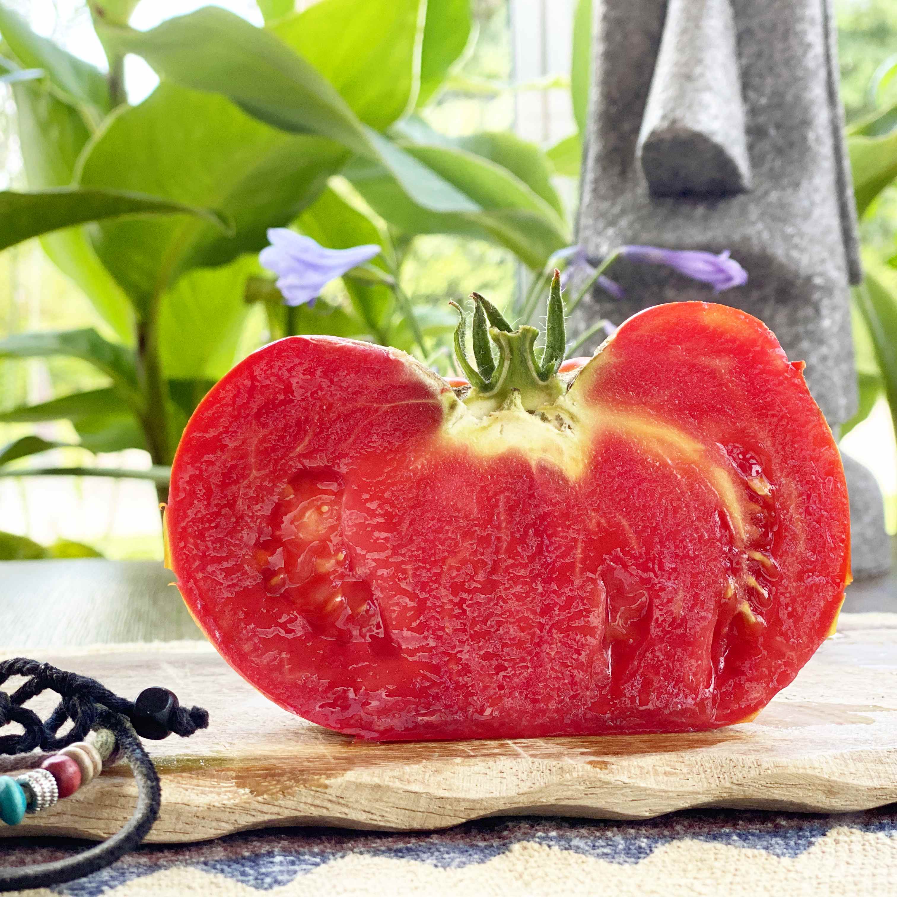 Eine ovale rote quer aufgeschnittene Tomate auf Brett